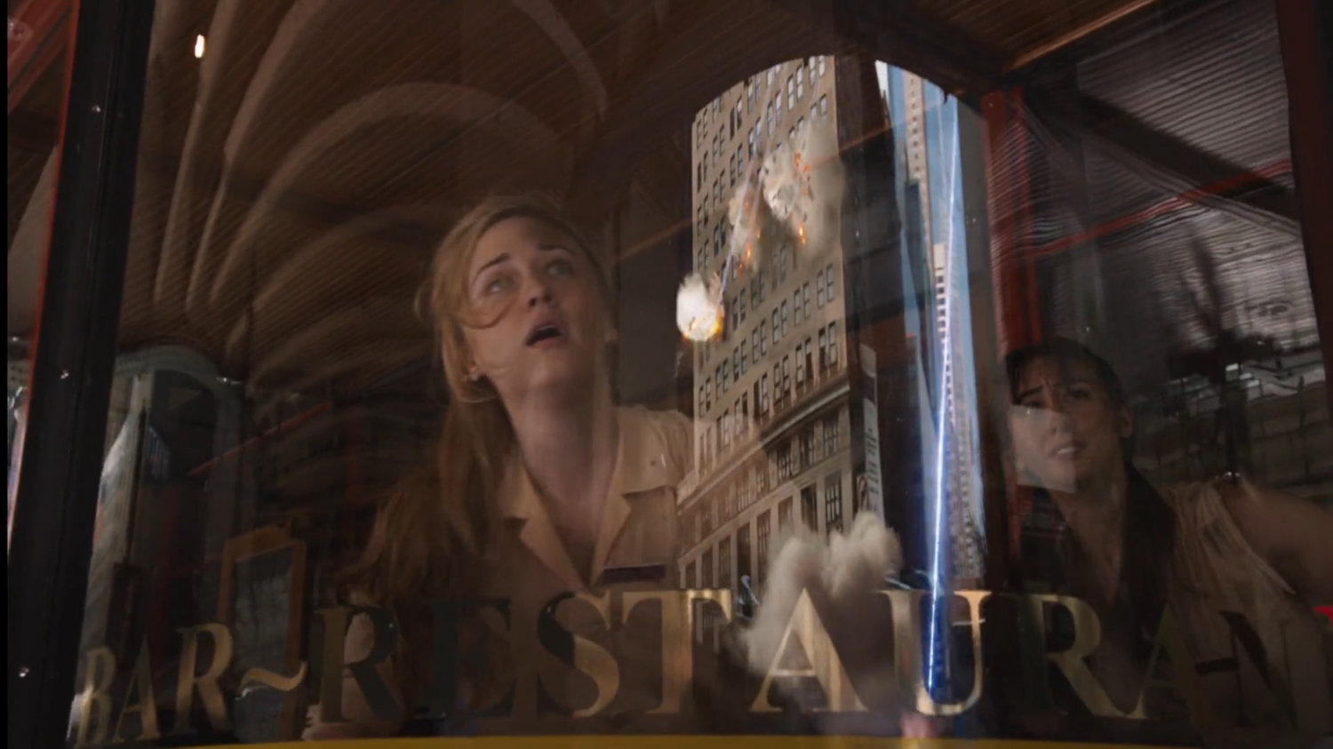 Waitress looking up through window as a building explodes, reflected in the glass.
