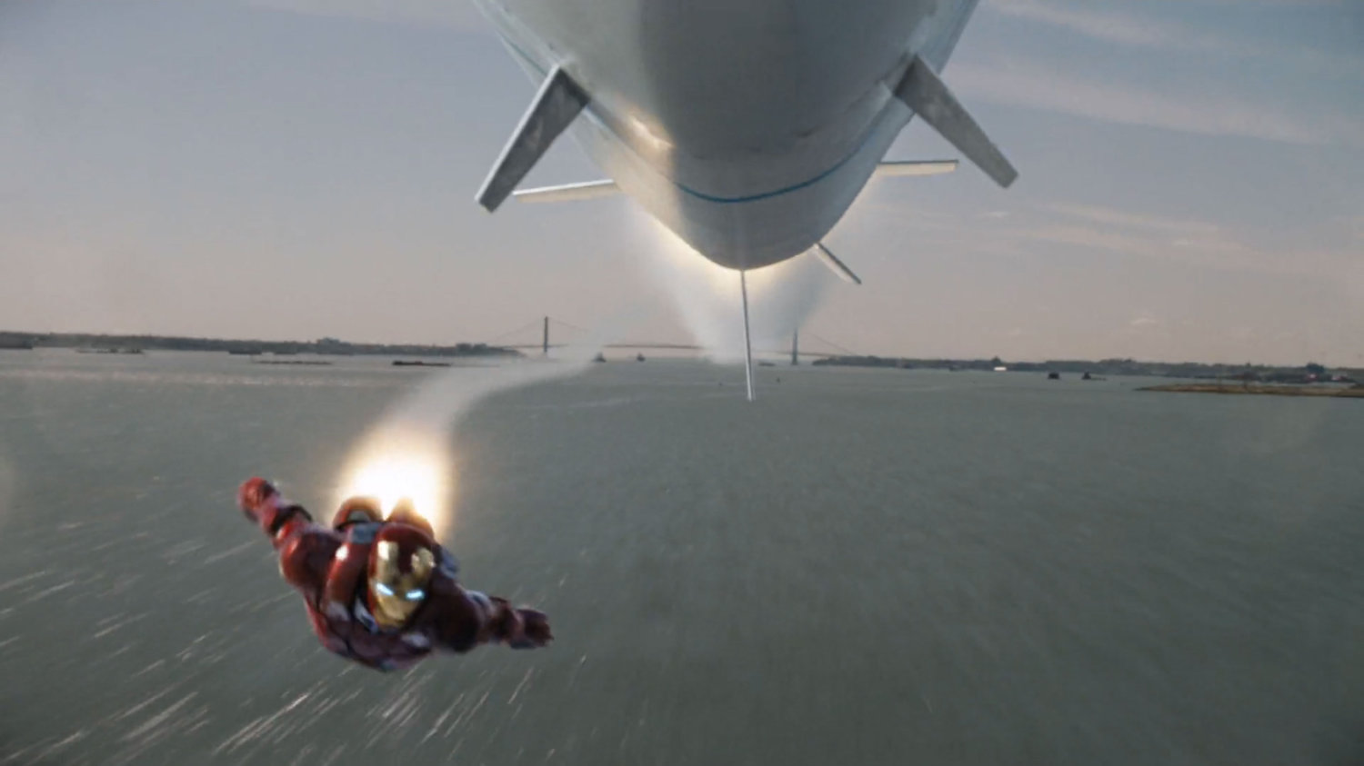 Iron Man maneuvers under a missile with the Verrazano-Narrows Bridge in the background.