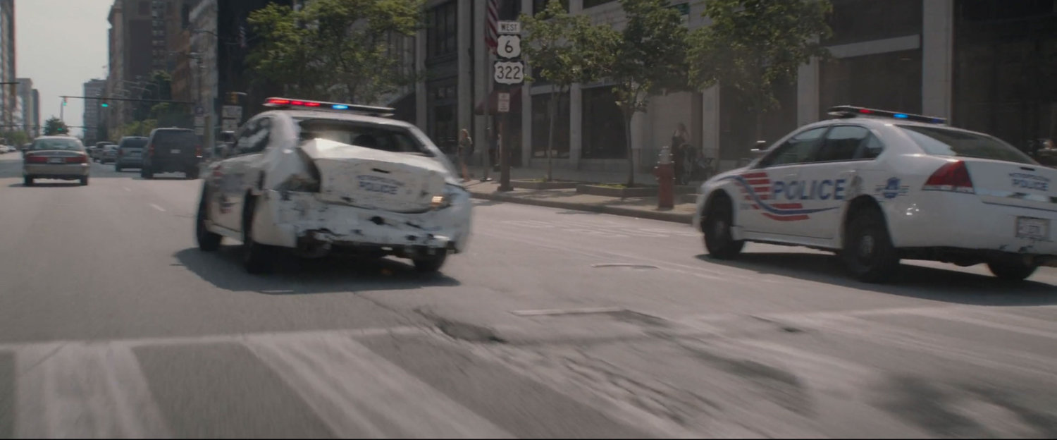 Two police cars pursue.