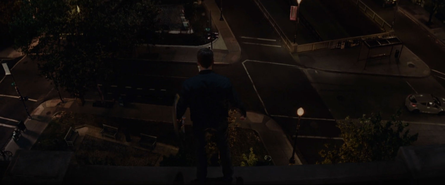 Nighttime shot of silhouetted figure on rooftop looking over Washington DC neighborhood.