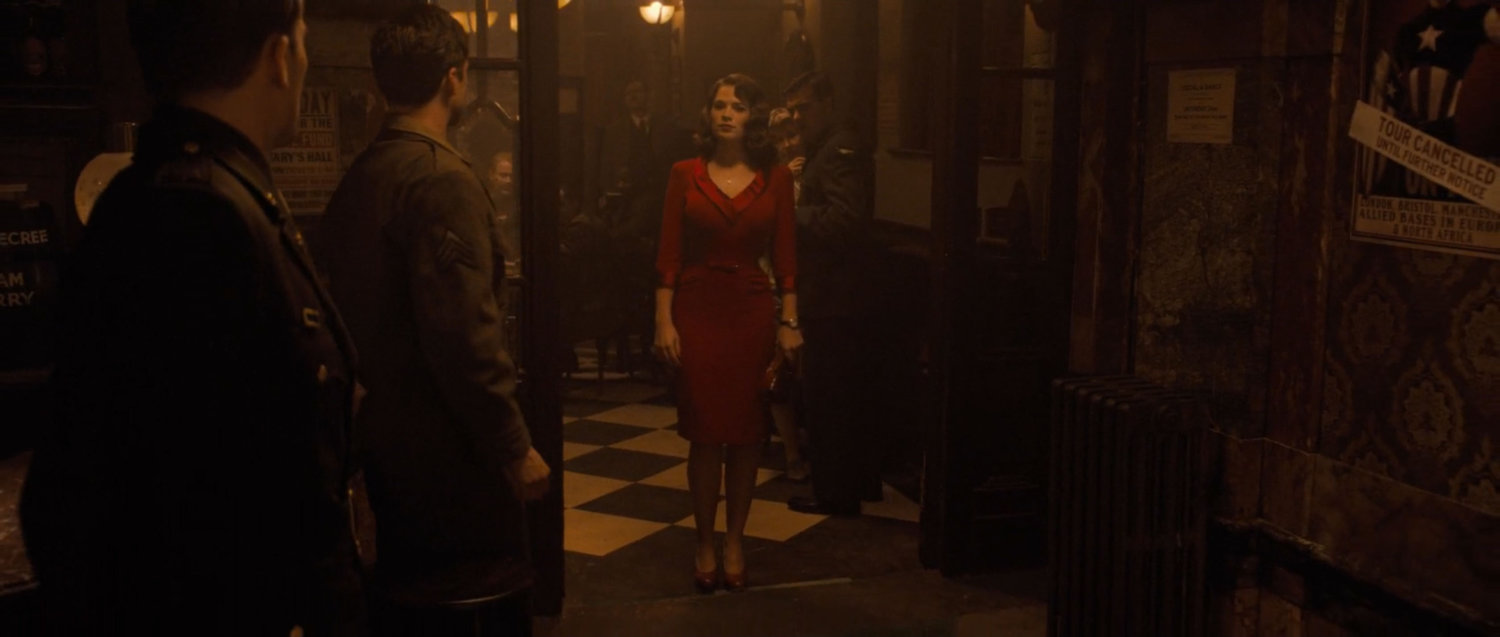 Peggy Carter in a red dress in a London pub.