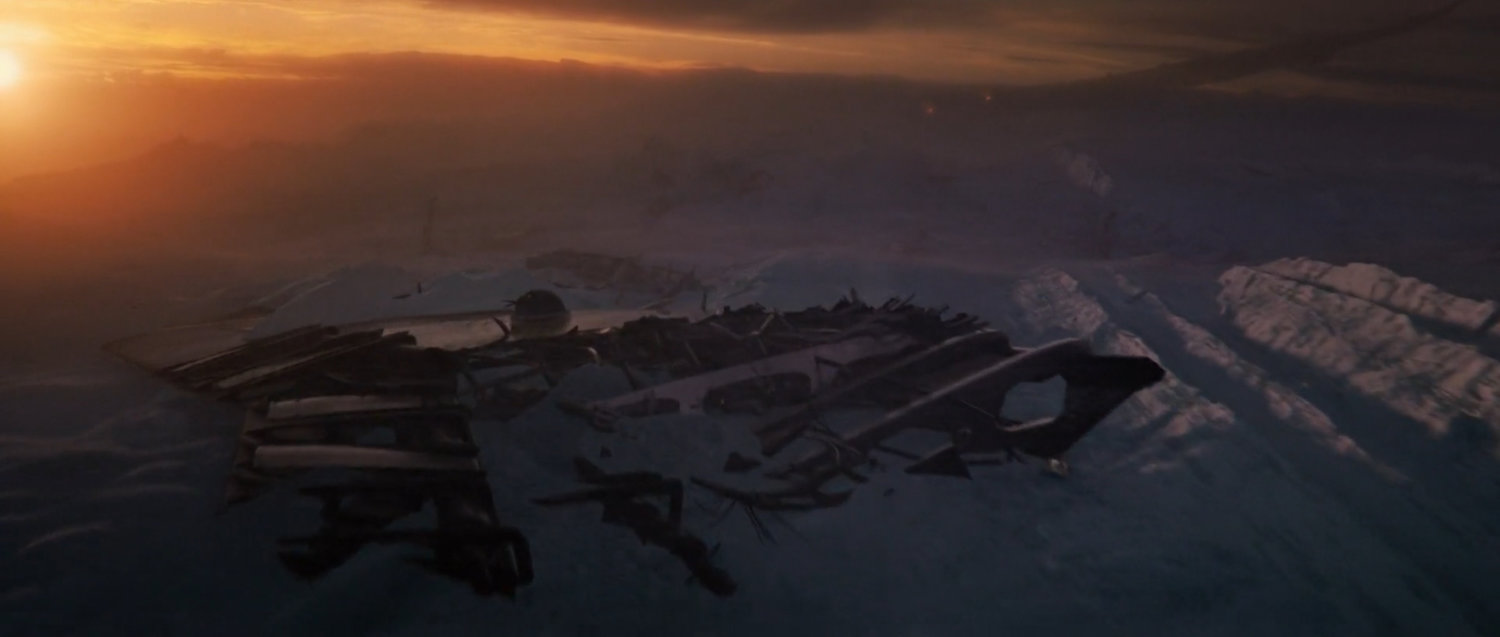 Airplane wreckage in the snow at sunset.