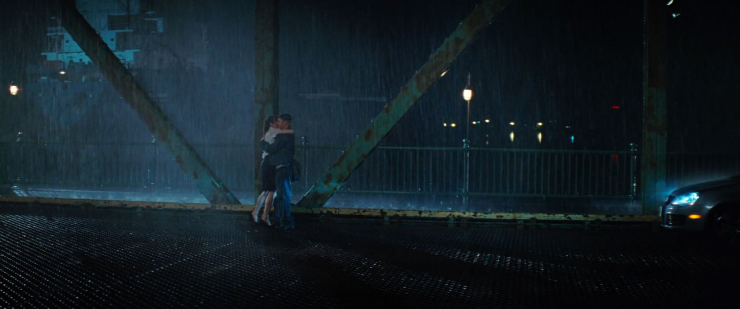 Bruce and Betty embrace on a bridge in the rain.