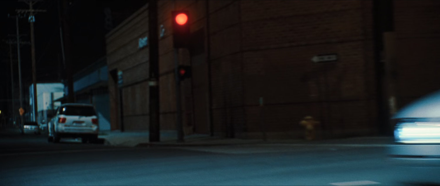 Nighttime street corner from car POV.