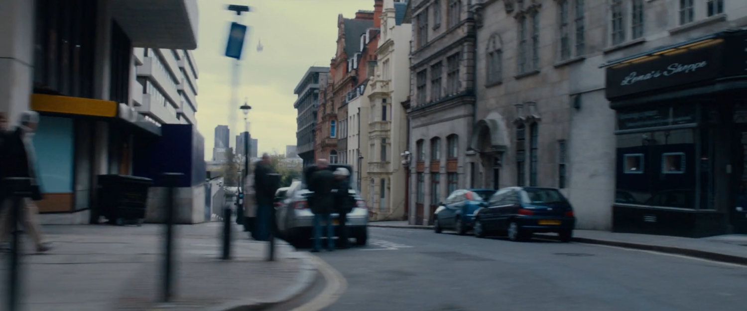 A London street with cars parked on the sides.