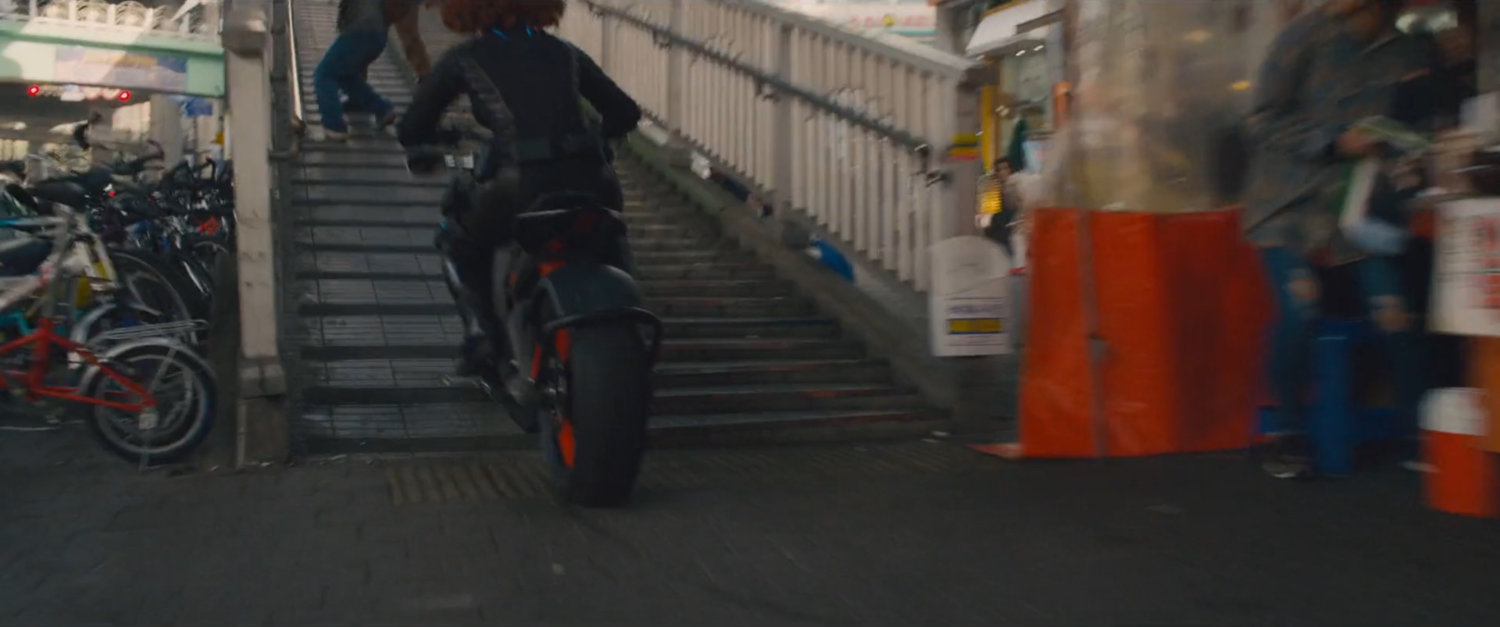 The Black Widow on a motorcycle speeds up a staircase.