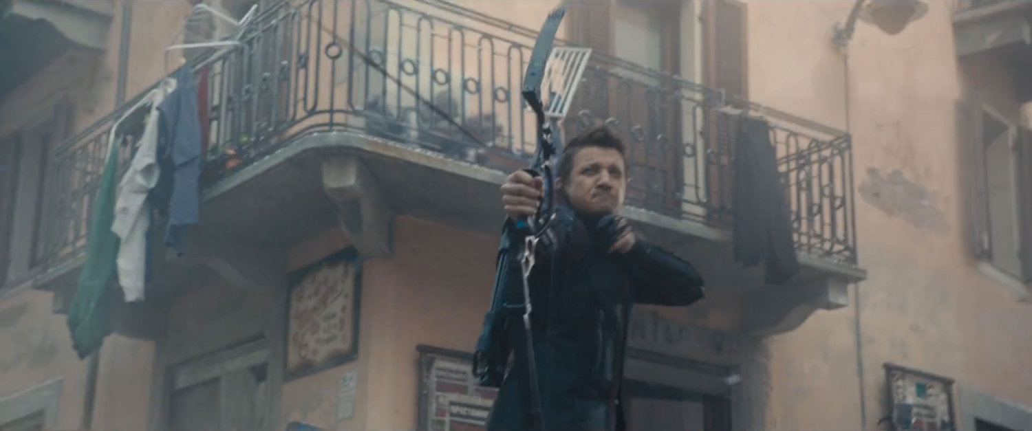Hawkeye fires an arrow outside a Novi Grad building with balcony.