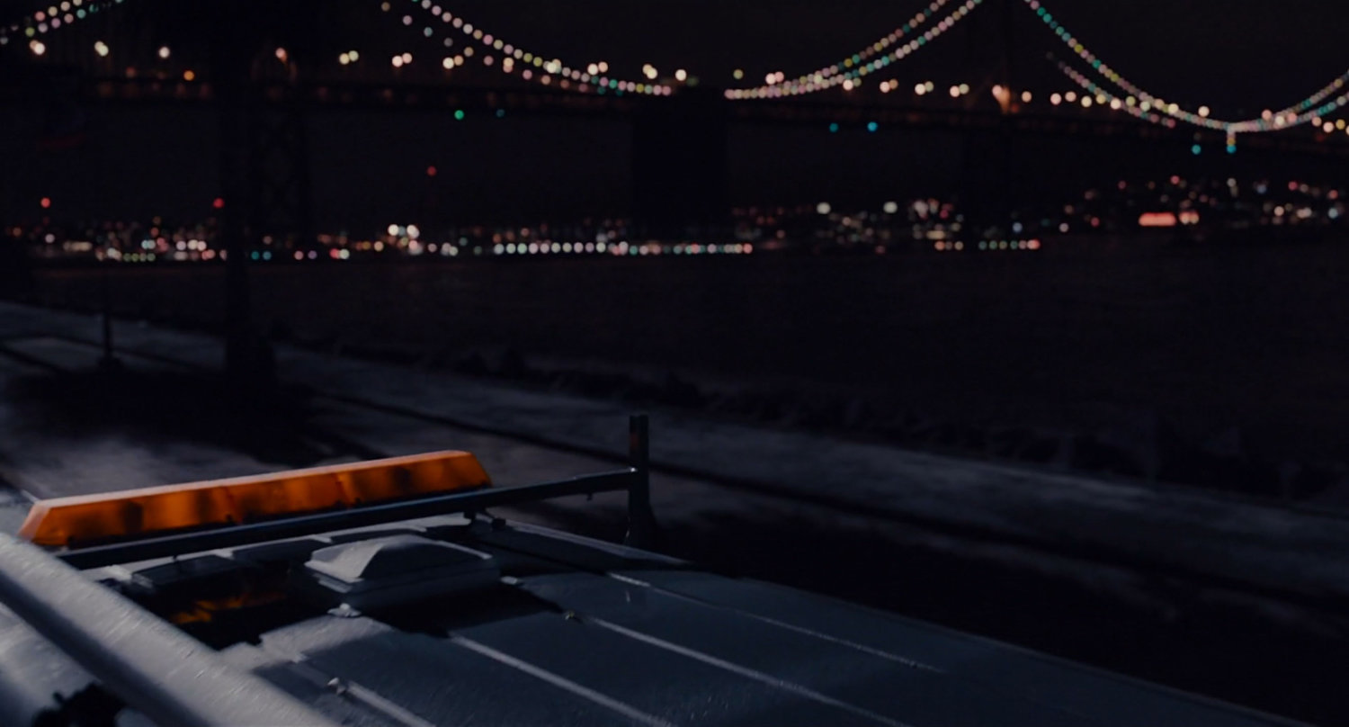 Nighttime shot of road with Bay Bridge in background.