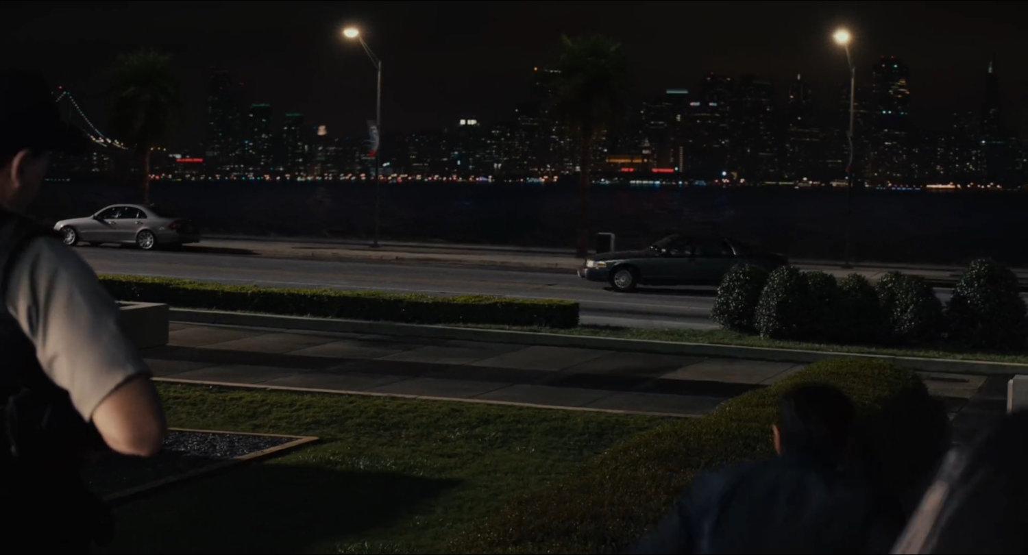 Nighttime view of road with downtown San Francisco across the bay.