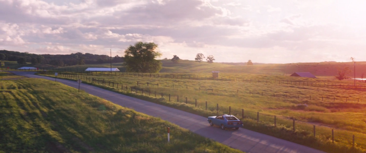 High angle of road at sunset with car.