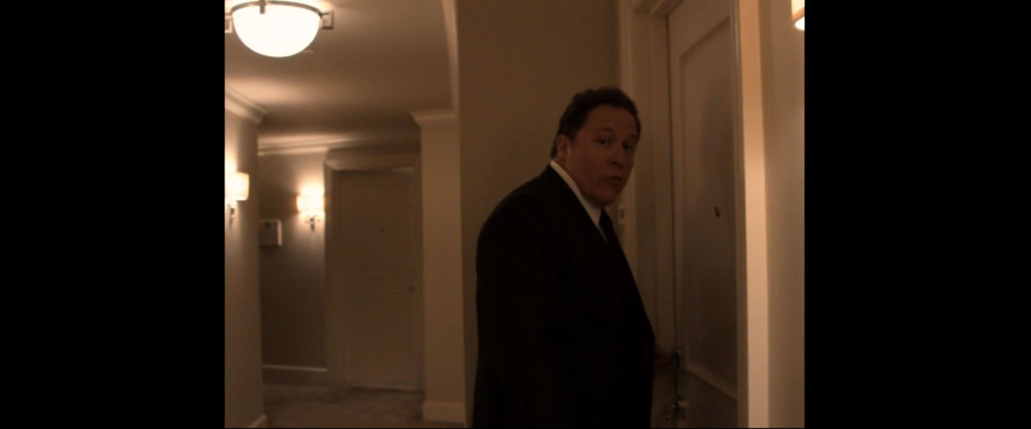 Happy Hogan entering hotel room.