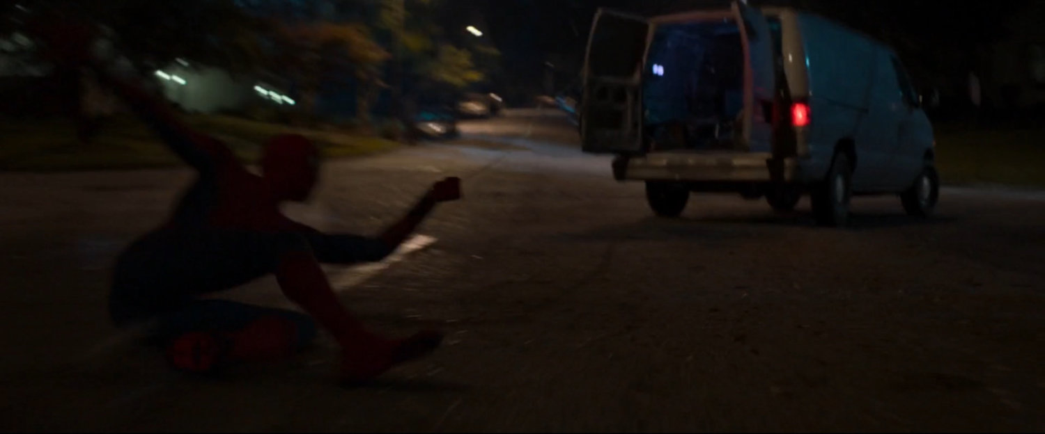 Spider-Man dragged by webbing behind van.