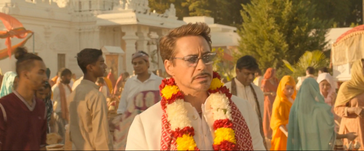 Tony Stark and a crowd in front of an ashram.