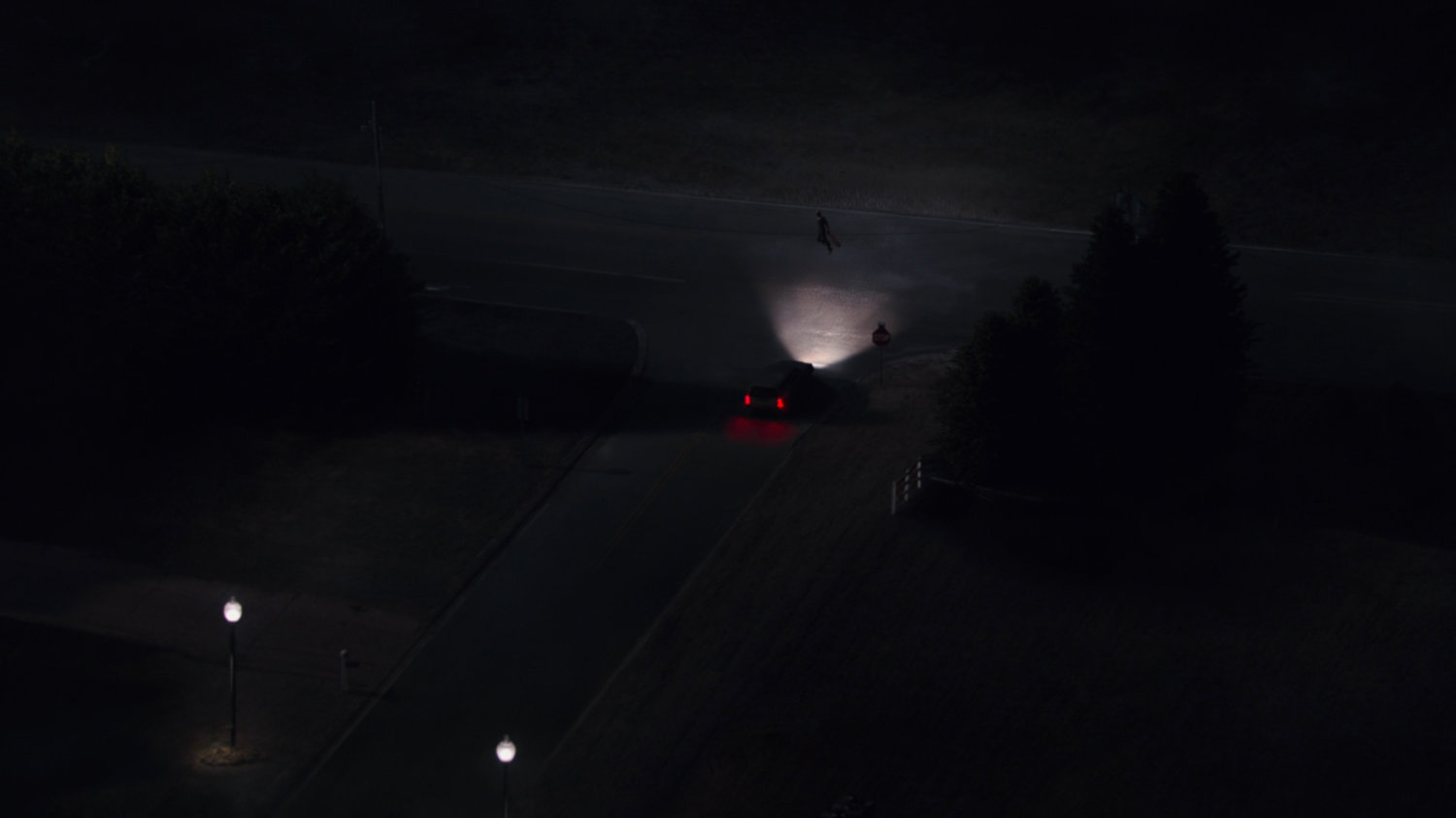 A car stopped at an intersection at night at the edge of Westview.
