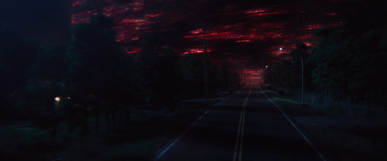 A red sky above a road at night.