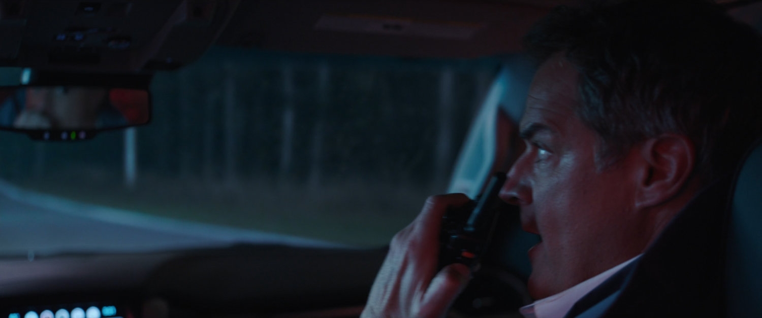 Director Hayward on walkie talkie in car.