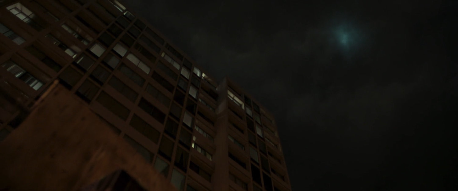 Looking up at the side of an apartment building at night.