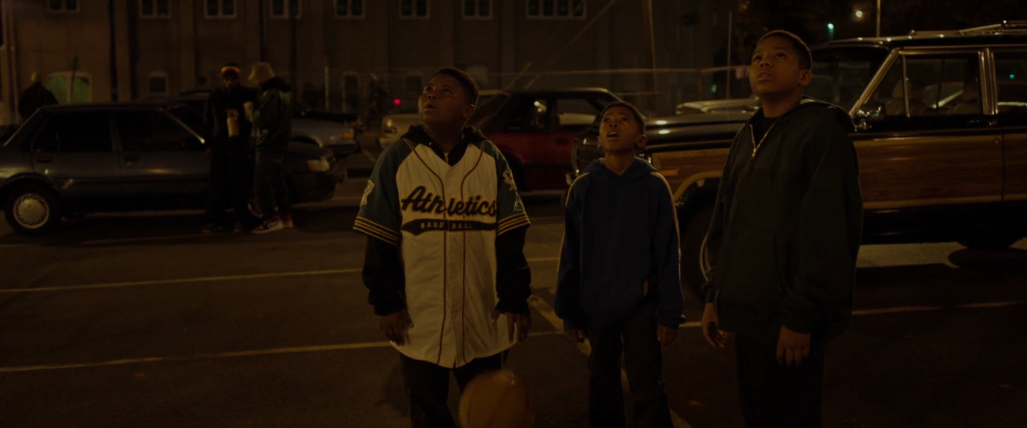 Three young boys looking up into the night sky.