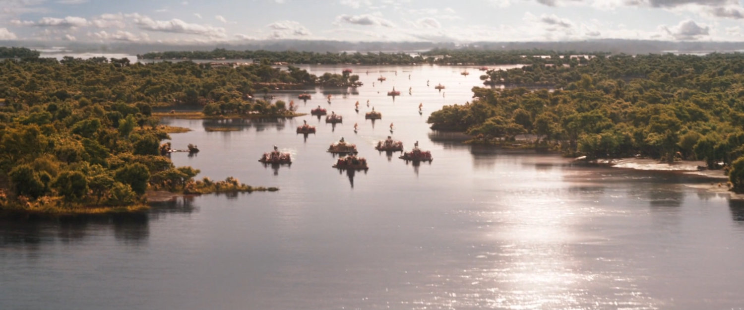 Wakanda tribes float on barges down a river toward the falls.