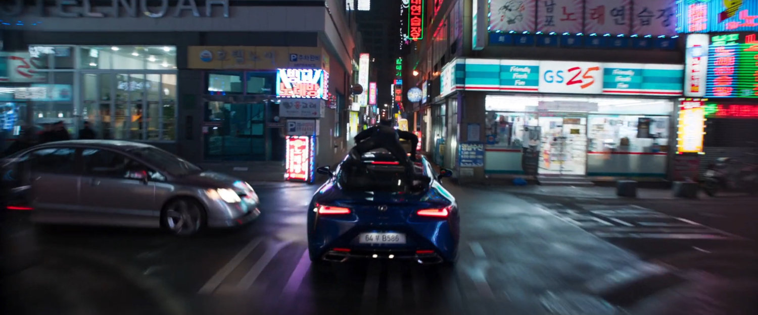 Black Panther atop a car driving through a narrow Busan street.