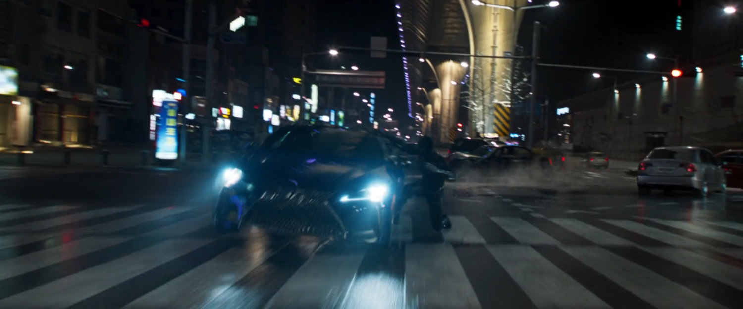 Black Panther hangs off the side of a car on a wide Busan road.