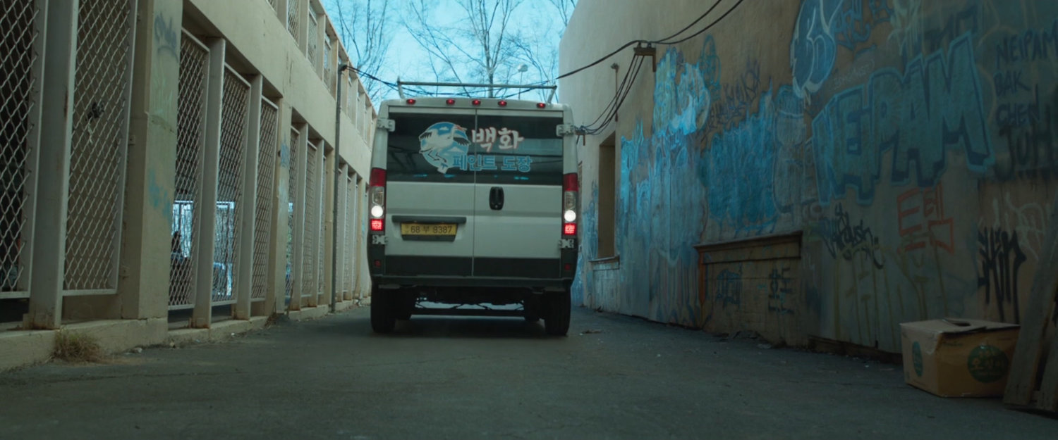 A white van backs down an alley.