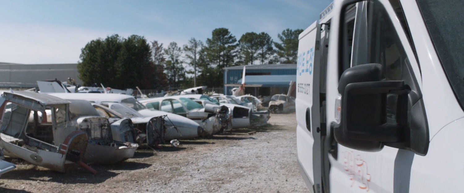 A white van drive through an airplane graveyard.