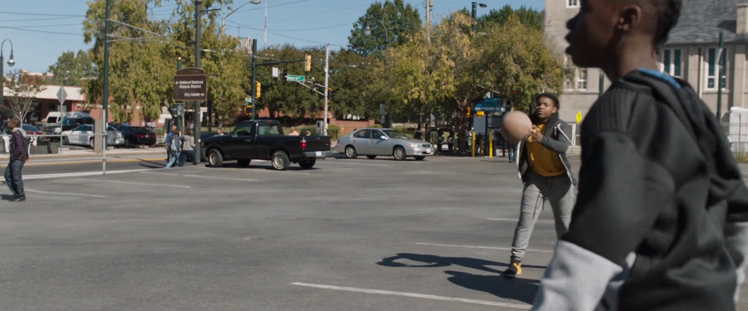 Two young boys playing basketball in a parking lot.
