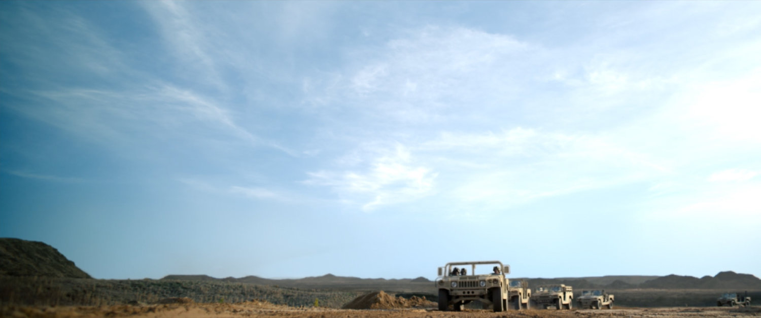 Low angle of humvees on desert road.