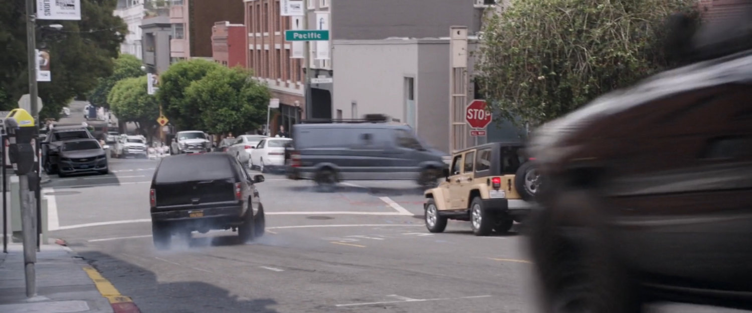 SUV chasing van around corner on San Francisco street.