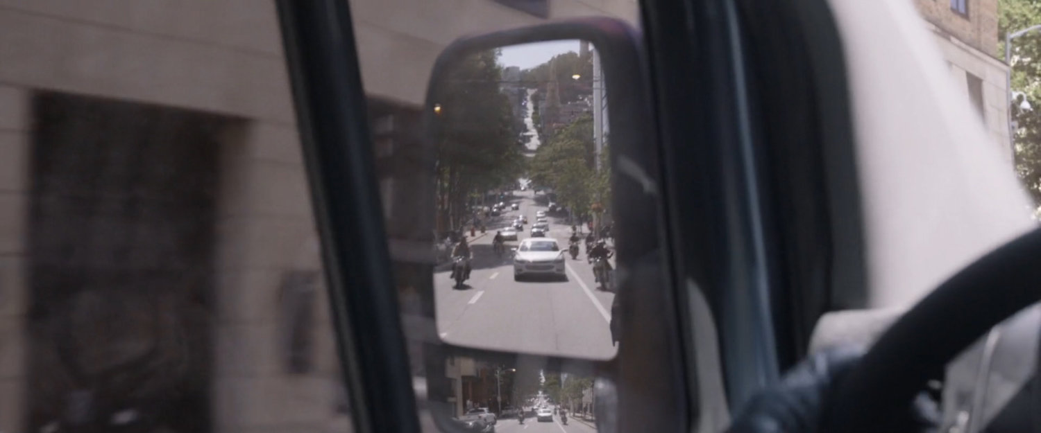 Motorcycles follow the van as seen in the side mirror.