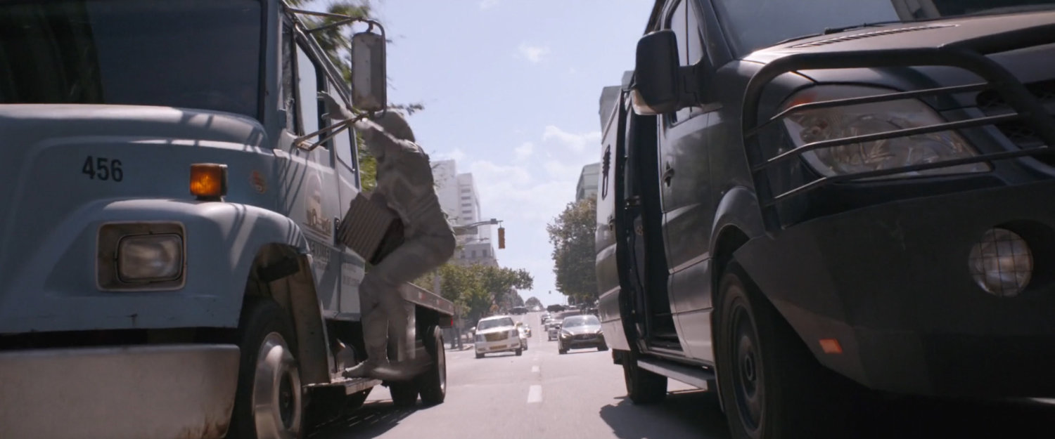 The Ghost on a side of flatbed truck with van speeding next to it.