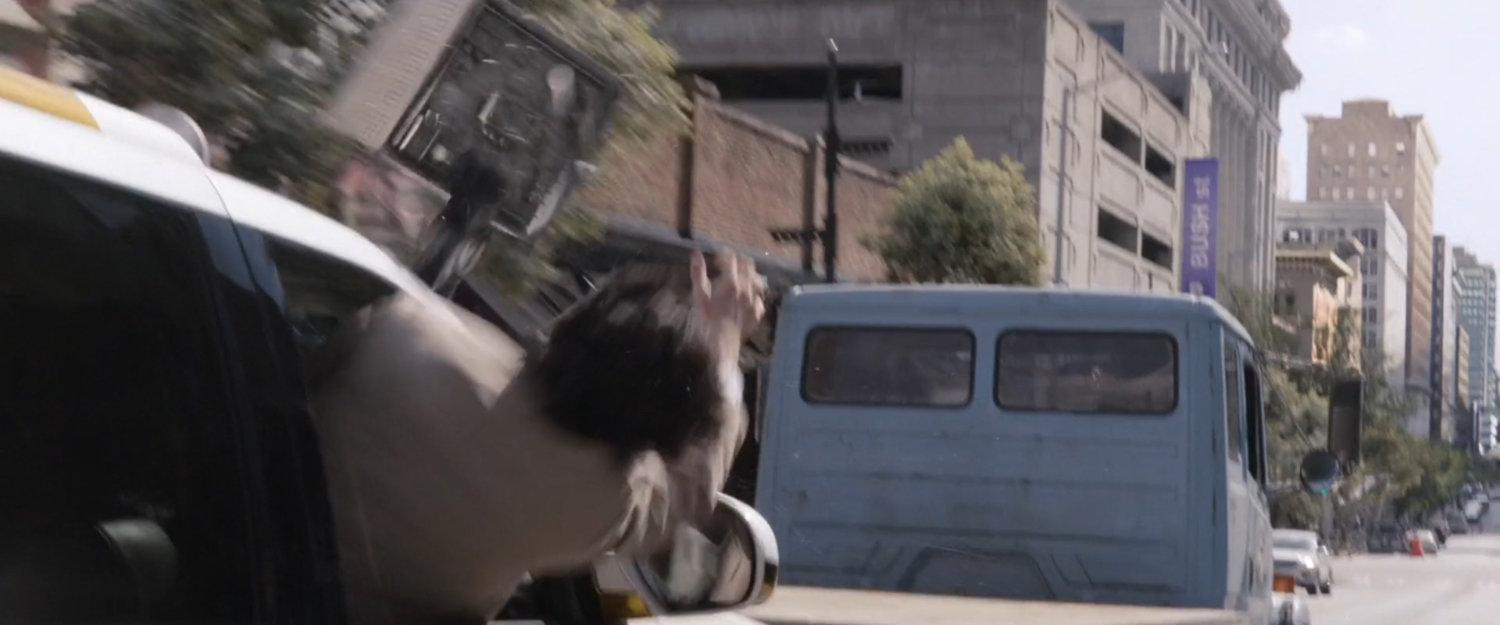 Sonny grabbing the miniature lab from a following SUV.