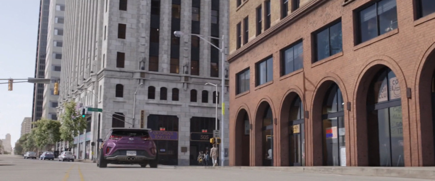 Purple car races off towards corner.