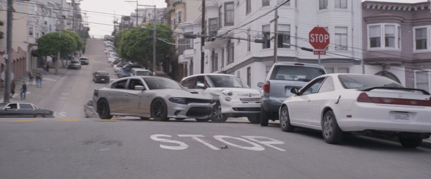 Two pursuit cars crash into parked cars.