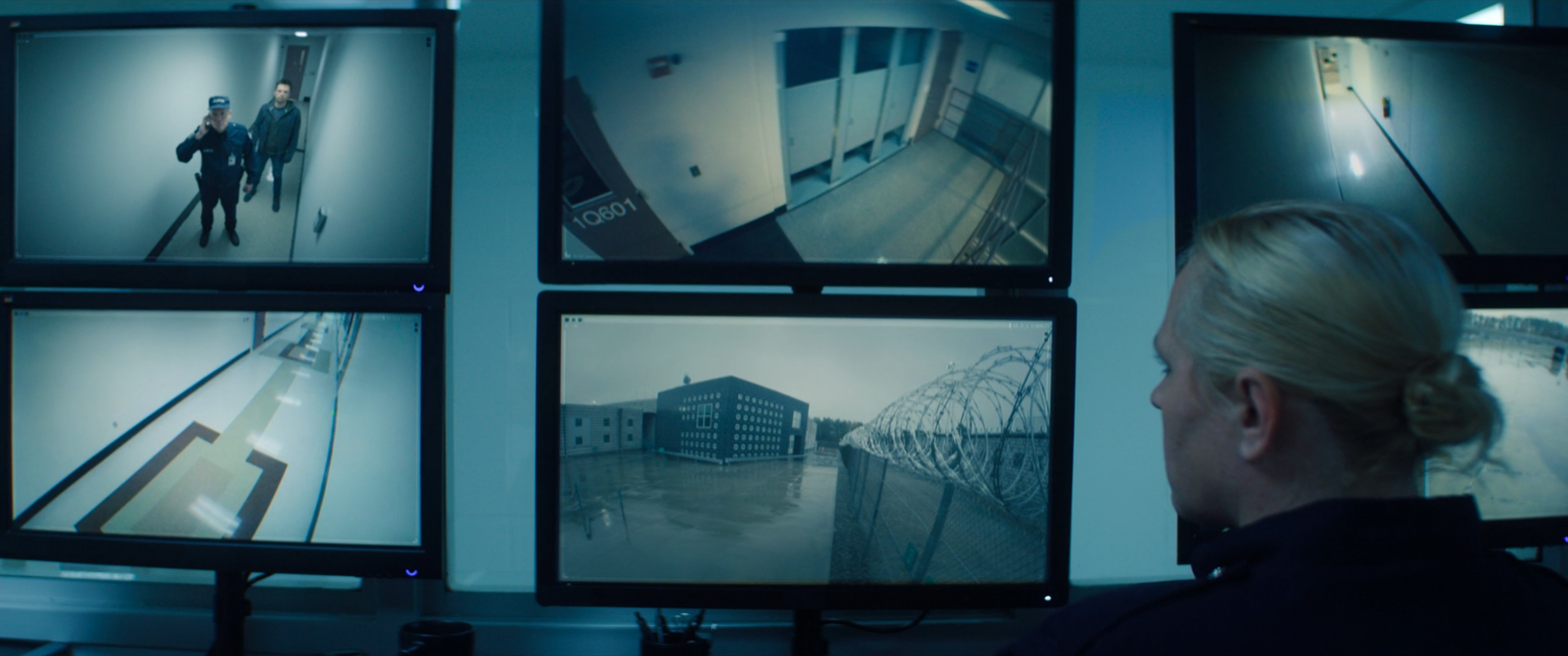 A prison guard looking at security monitors.