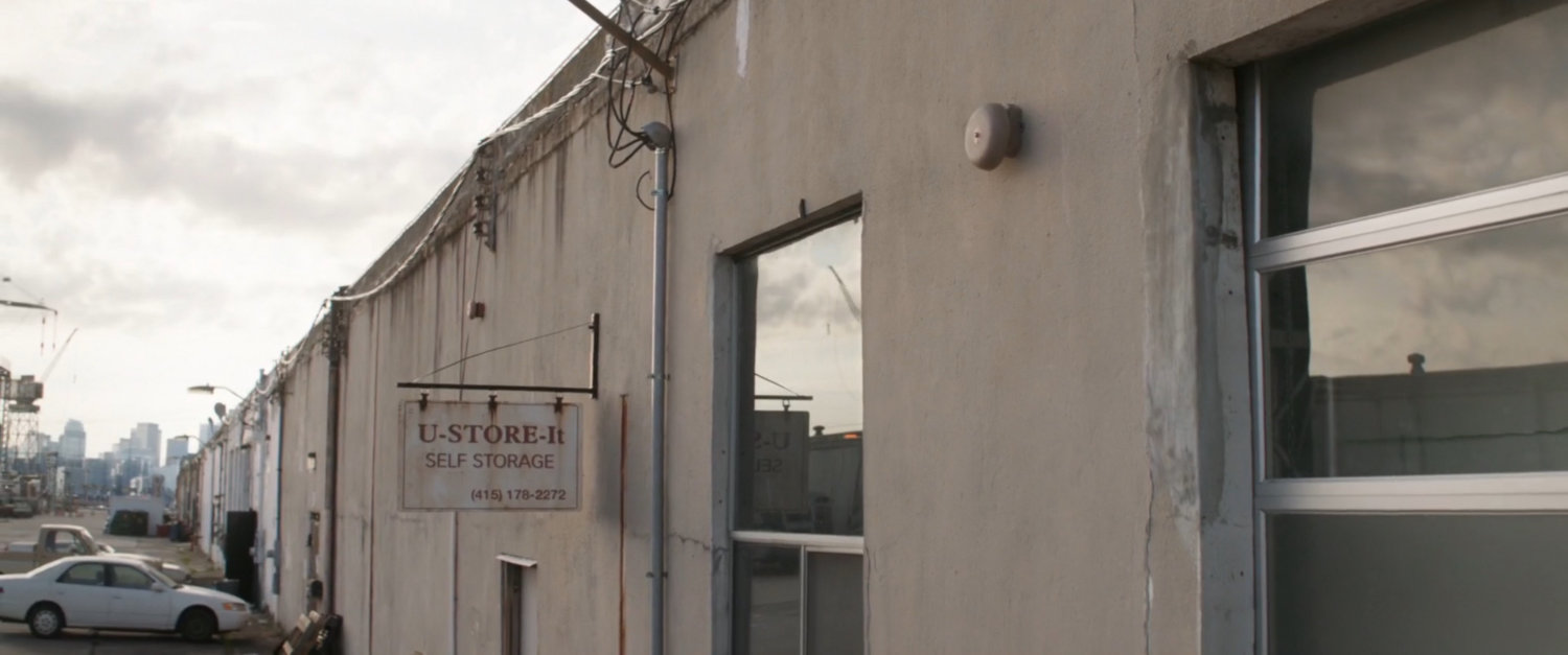 A sign for U-Store-It Self Storage on the side of an industrial warehouse.