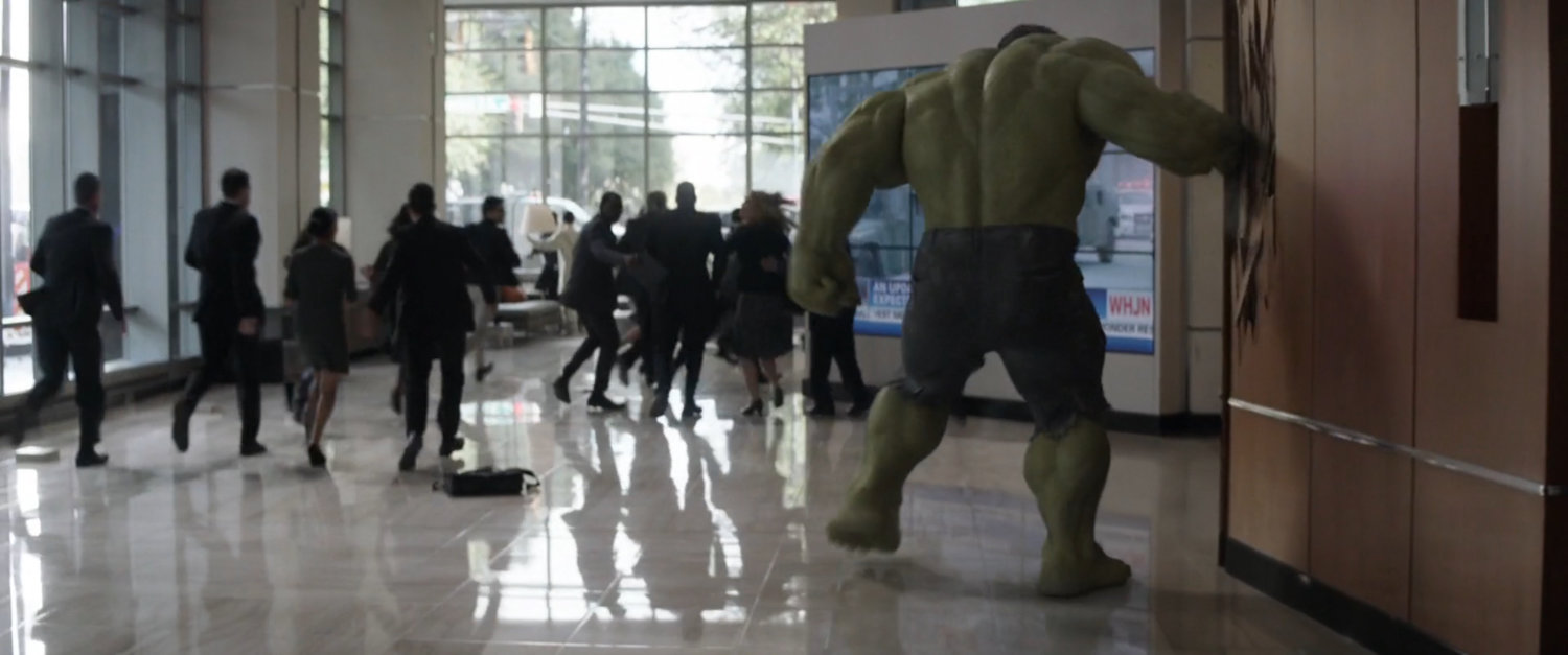 Hulk smashes a wall panel in the Stark tower lobby.