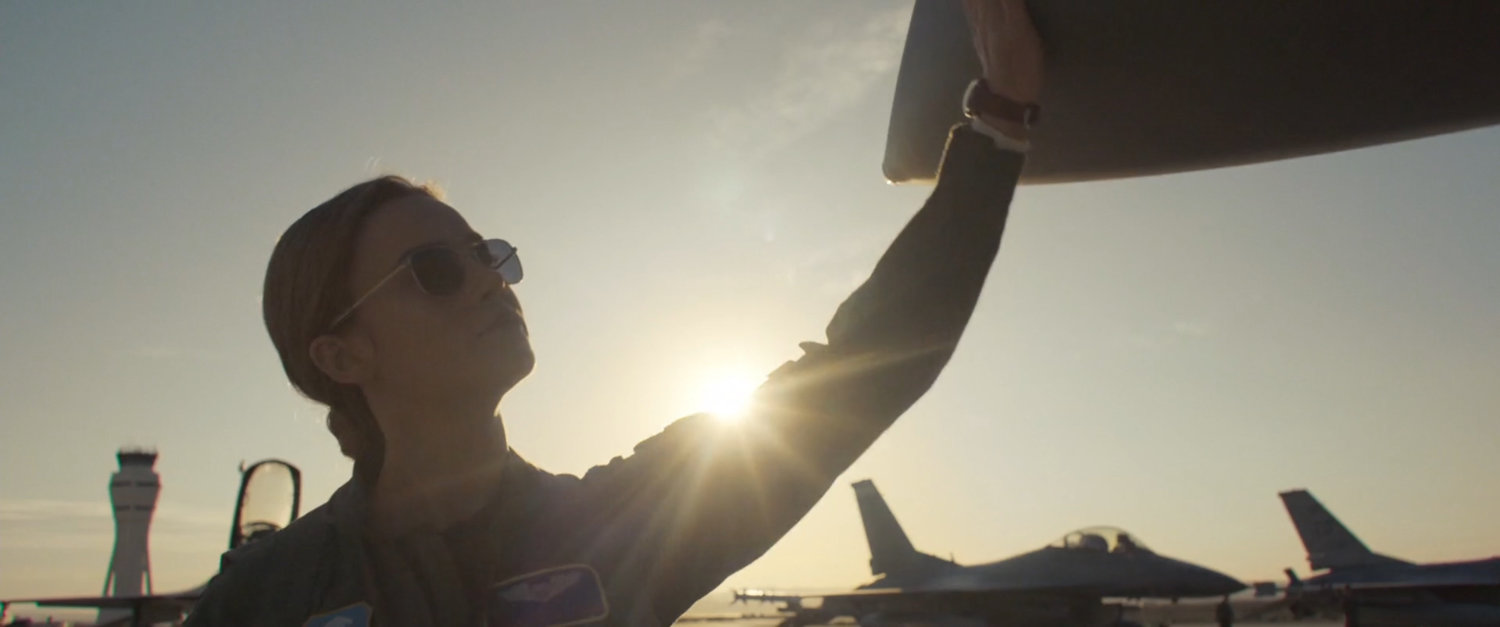 Carol Danvers touches the nose of her fighter plane.
