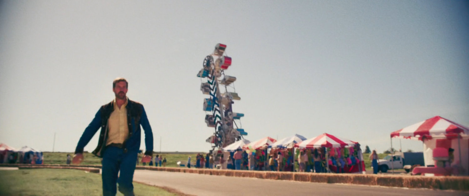 A man running on the side of a go cart track at a fair.