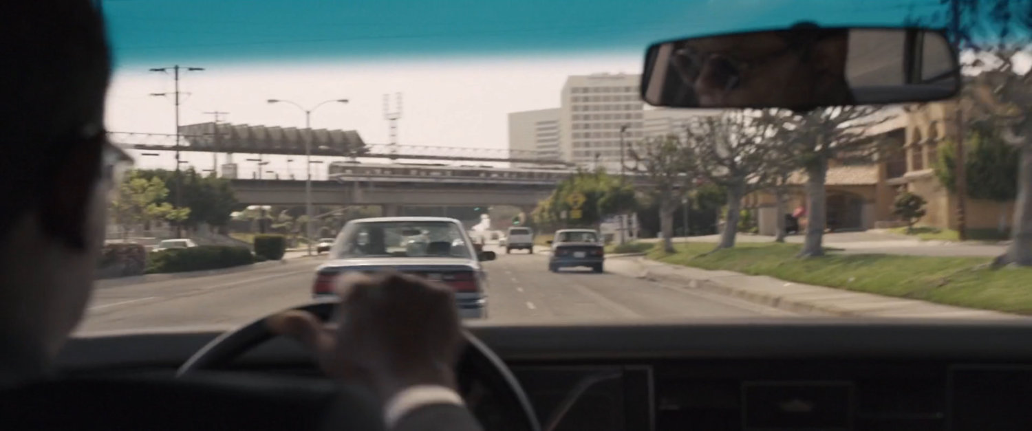 POV of Nick Fury's car racing down Los Angeles street toward Metro overpass.