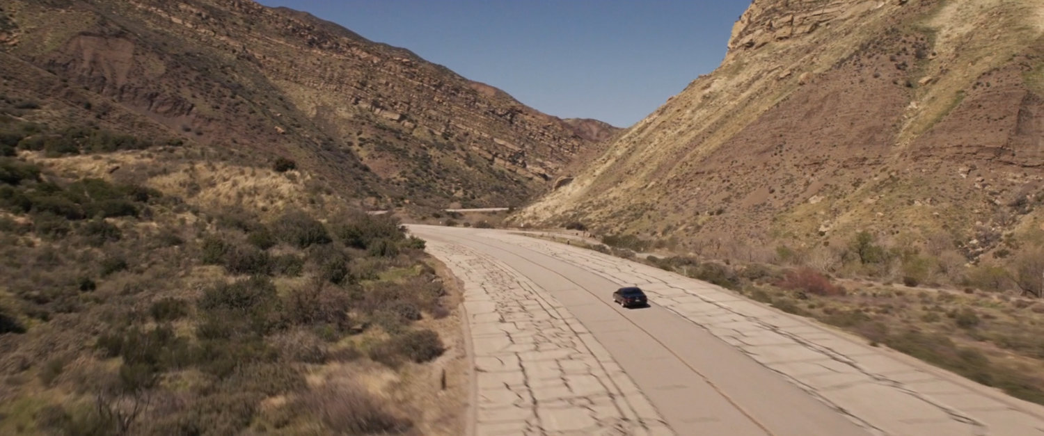 Nicky Fury's car driving up a dusty highway.