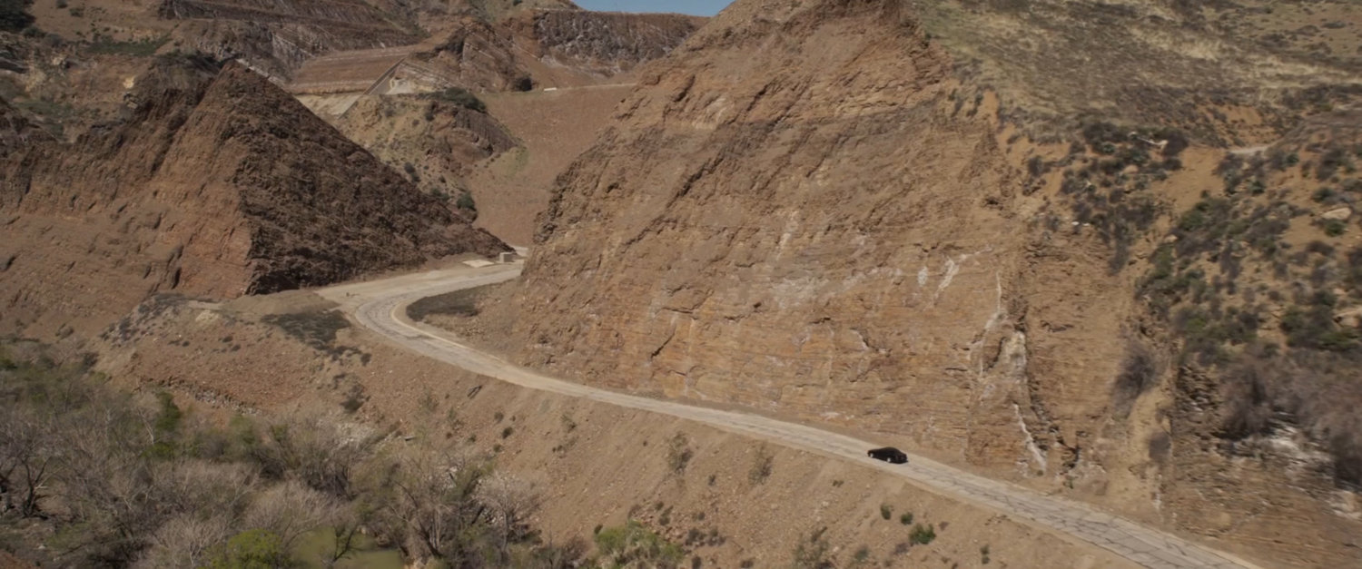 Aerial of car driving along  dirty mountain road.