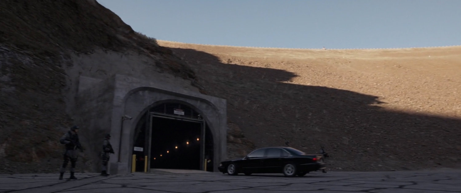 Car pulling up to guarded entrance tunnel.