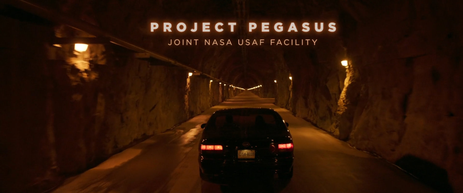 Car driving through underground tunnel. Text: Project Pegasus Joint NASA USAF facility.