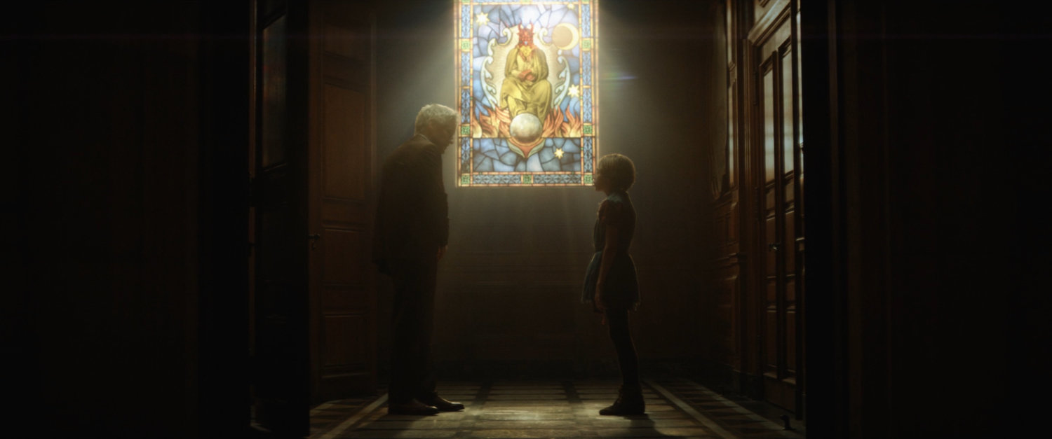 Mobius speaks to young boy by stained glass window.