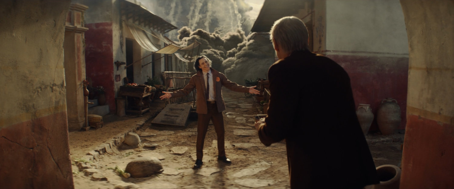 Loki standing before a wall of ash heading towards him in Pompeii.