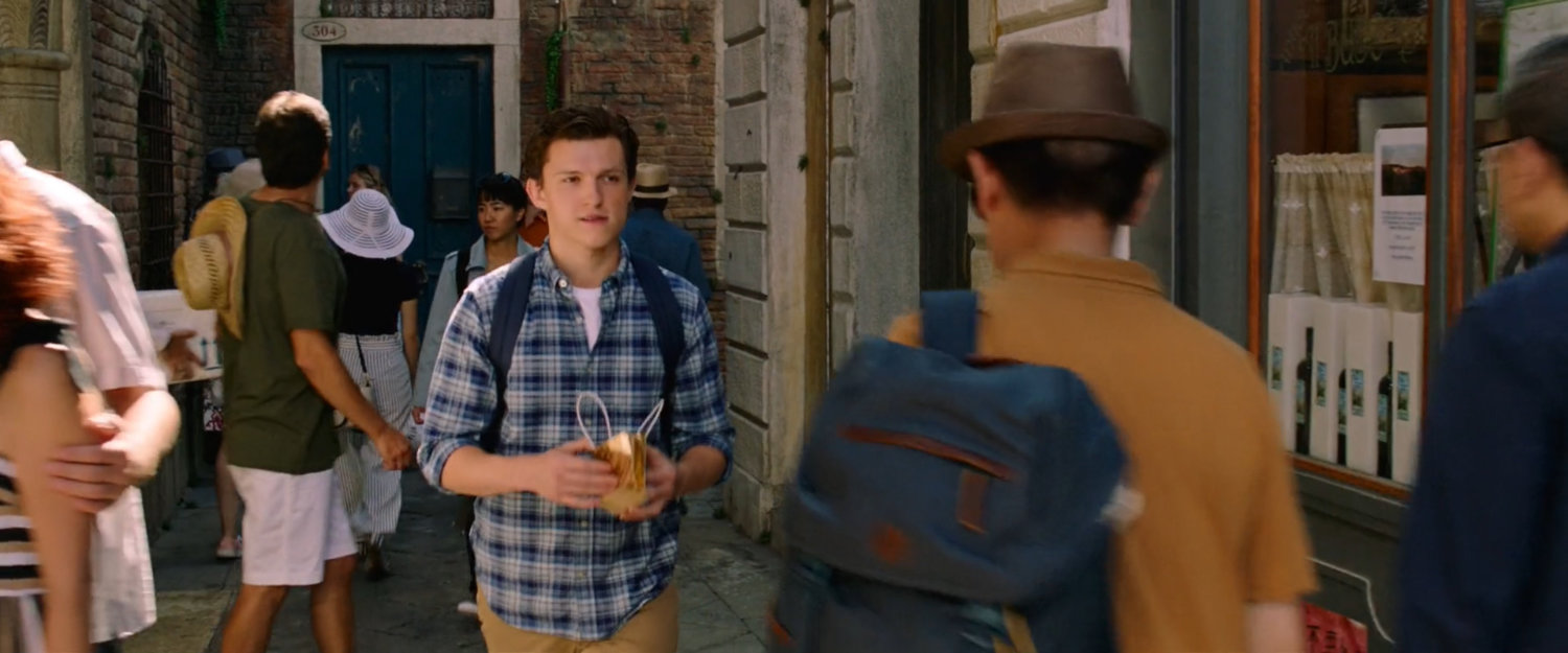 Peter Parker walks through a crowded alley in Venice.