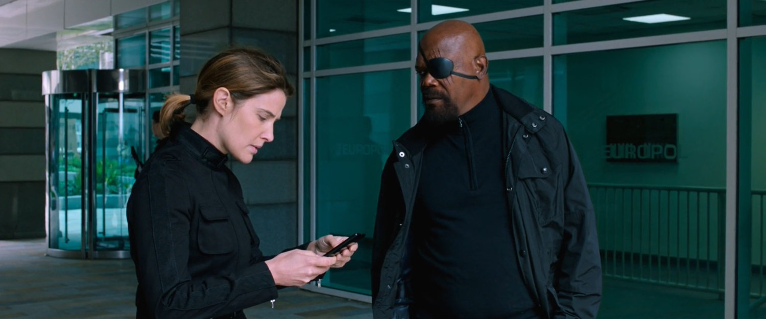 Maria Hill and Nick Fury outside modern office building.