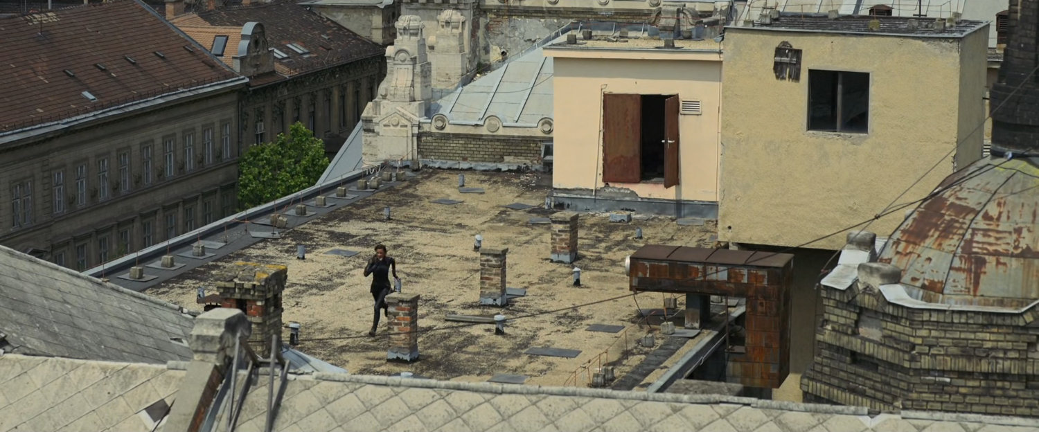 A woman running across a Budapest rooftop.